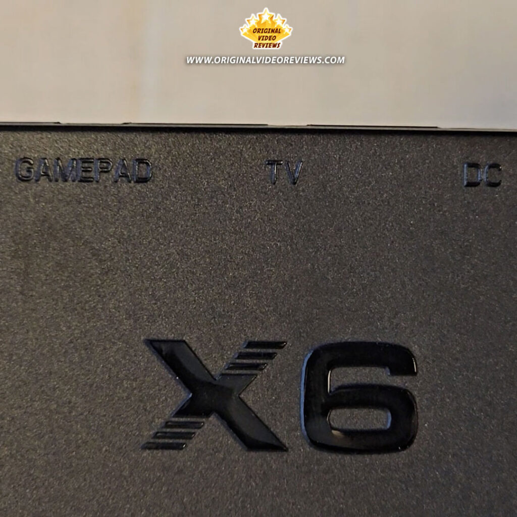 Close-up of the X6 handheld console showing GAMEPAD, TV, and DC input ports