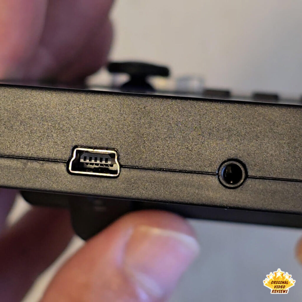 Close-up of the X6 handheld console's ports, showing the mini-USB port on the left and the AV output jack on the right.