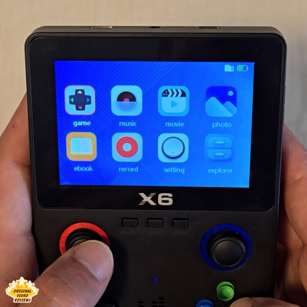 X6 handheld console home screen displaying app icons for games, music, movies, photos, ebooks, recording, settings, and file explorer.