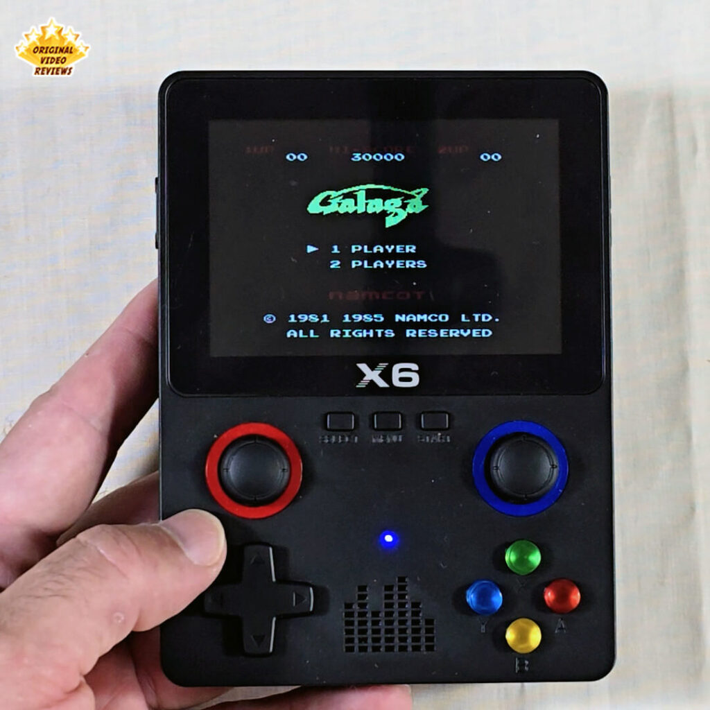 Title screen from Galaga on the X6 handheld console, showing player options for 1 or 2 players.