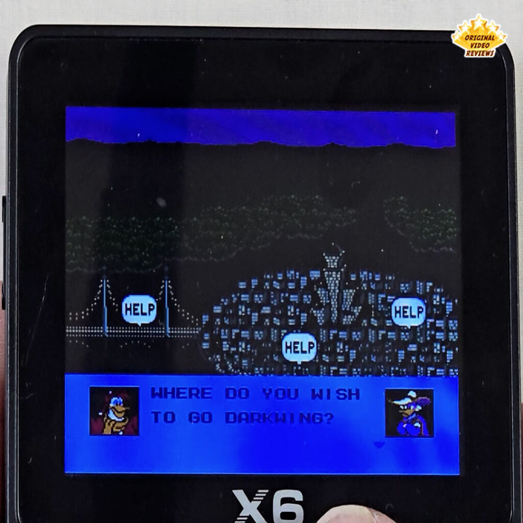 Title screen from Darkwing Duck on the X6 handheld console, showing a city map and character dialogue asking where to go next.