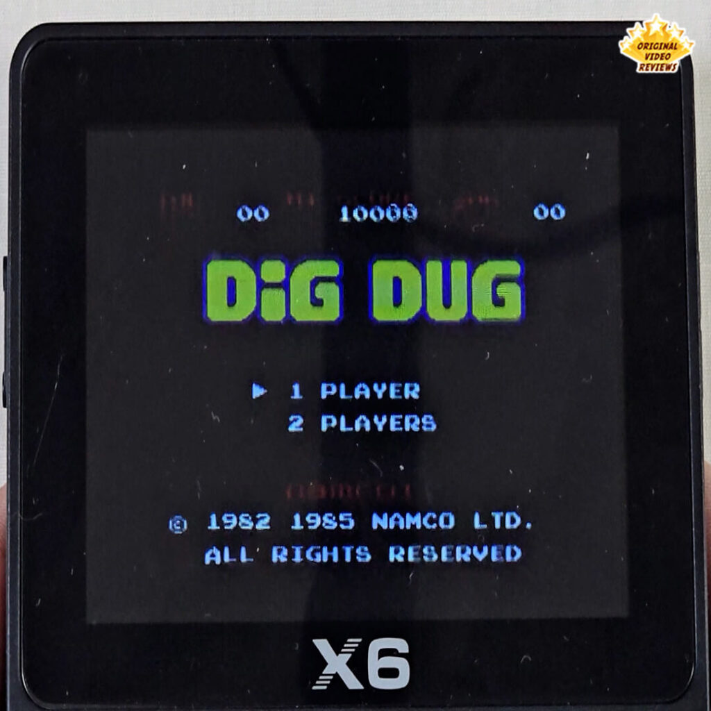 Title screen of Dig Dug displayed on the X6 handheld console, showing the classic arcade game's logo and single/two-player options.