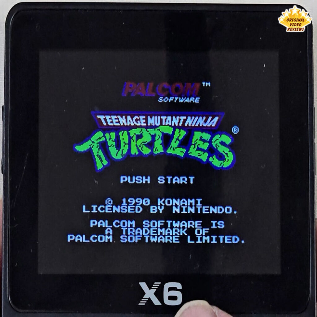 X6 handheld console displaying the title screen of Teenage Mutant Ninja Turtles by Konami (1990), licensed by Nintendo, PALCOM Software.