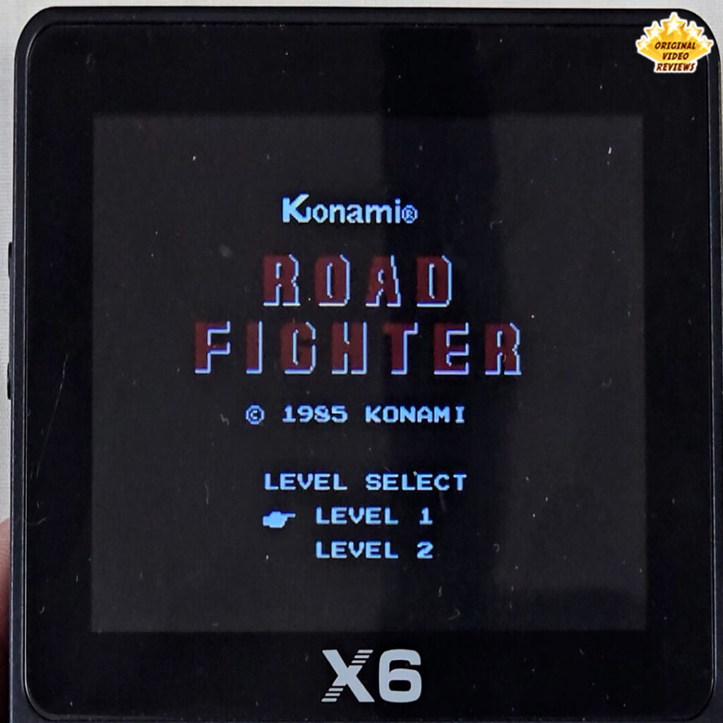 X6 handheld console displaying the title screen of Road Fighter by Konami from 1985, with level selection menu visible.