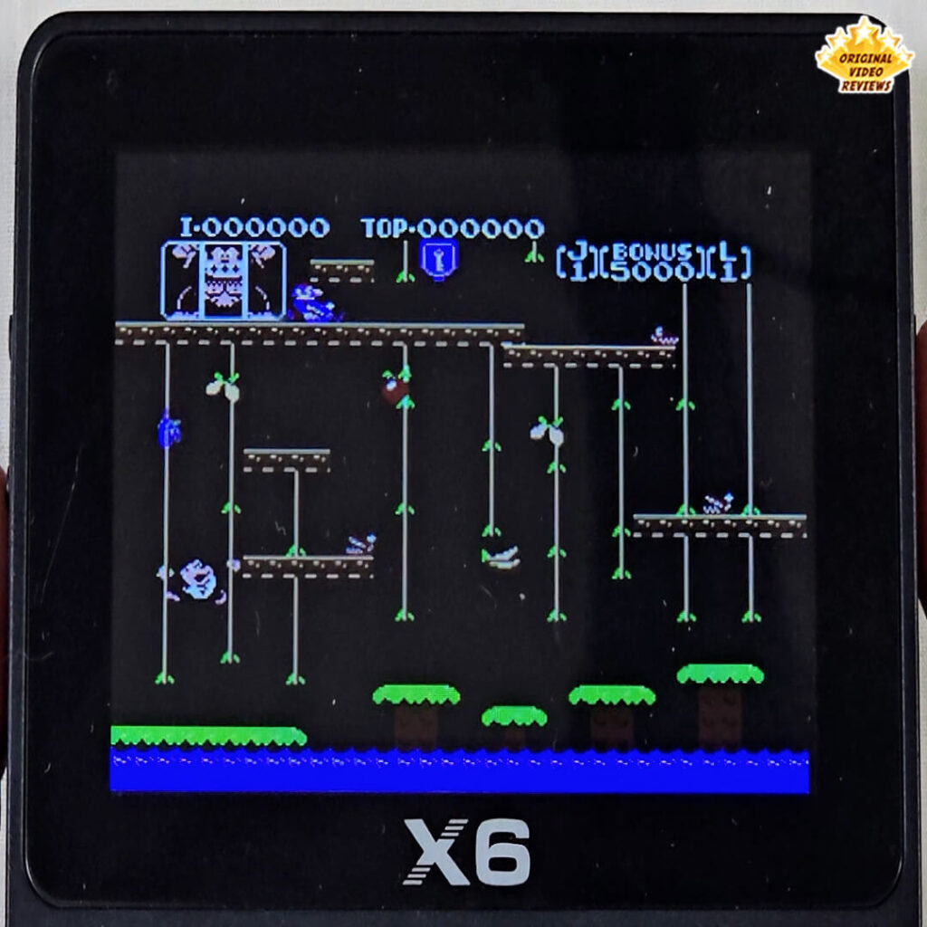 X6 handheld console displaying the classic arcade game Donkey Kong Junior with vines, platforms, and enemies on screen.