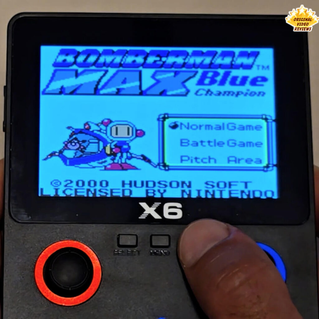 X6 handheld console displaying the title screen of the retro game Bomberman Max Blue Champion.