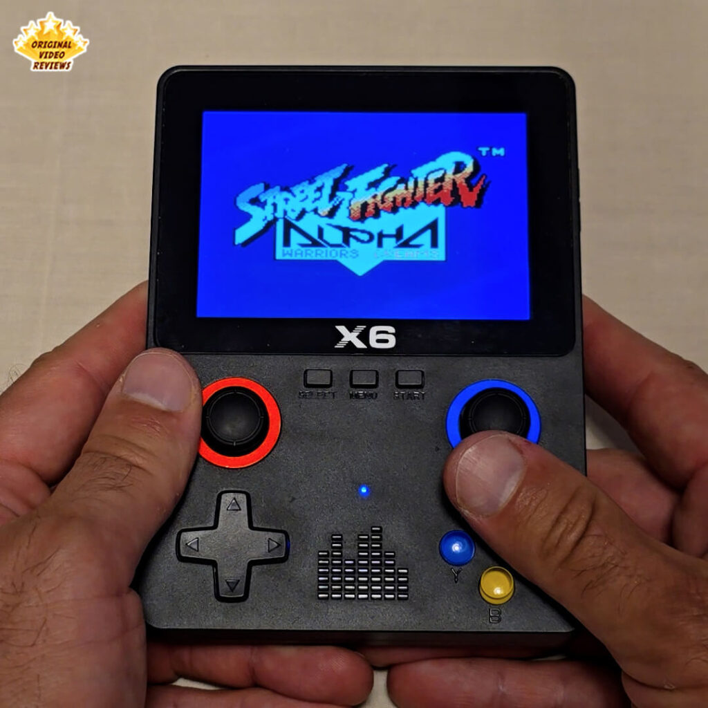 X6 handheld console displaying the title screen of the game Street Fighter Alpha Warriors' Dreams.