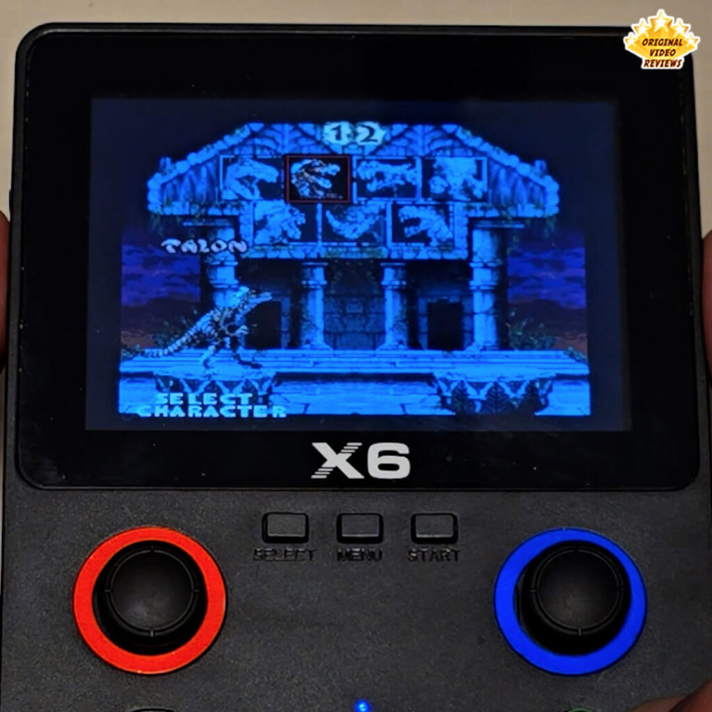X6 handheld console displaying the character selection screen from the game Primal Rage.