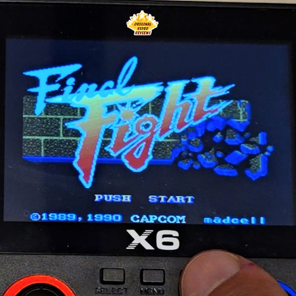 Close-up of the X6 handheld console displaying the title screen of Final Fight by Capcom.