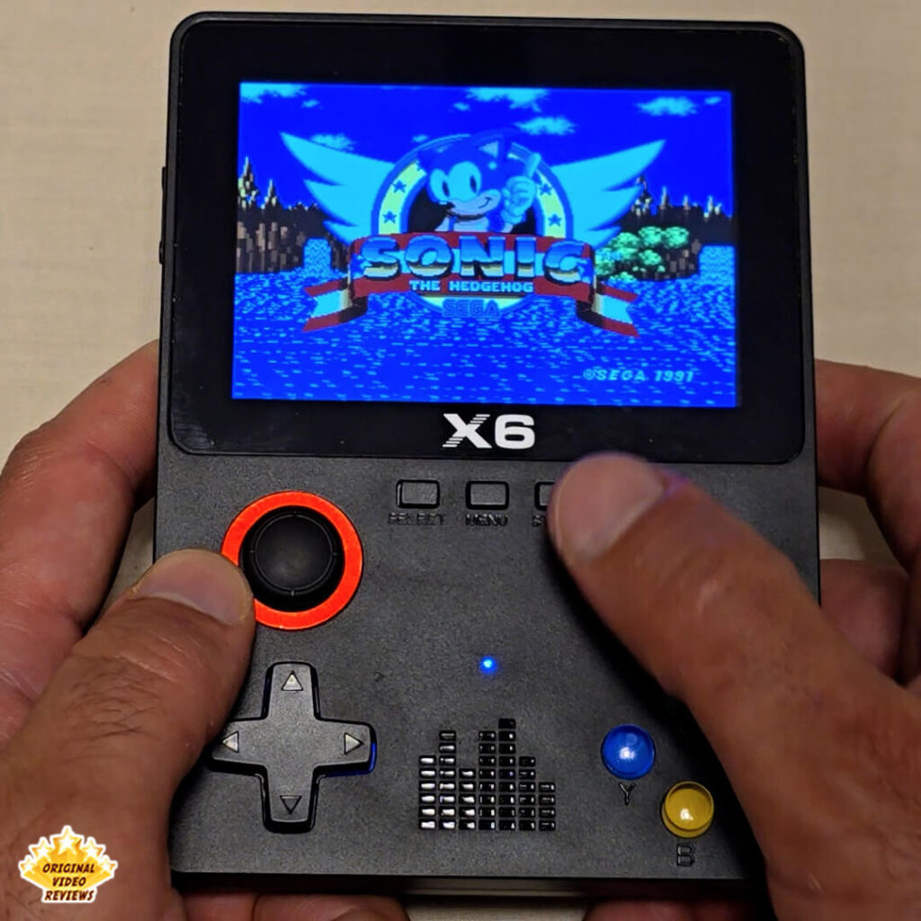 Close-up of the X6 handheld console displaying the title screen of Sonic the Hedgehog by SEGA.