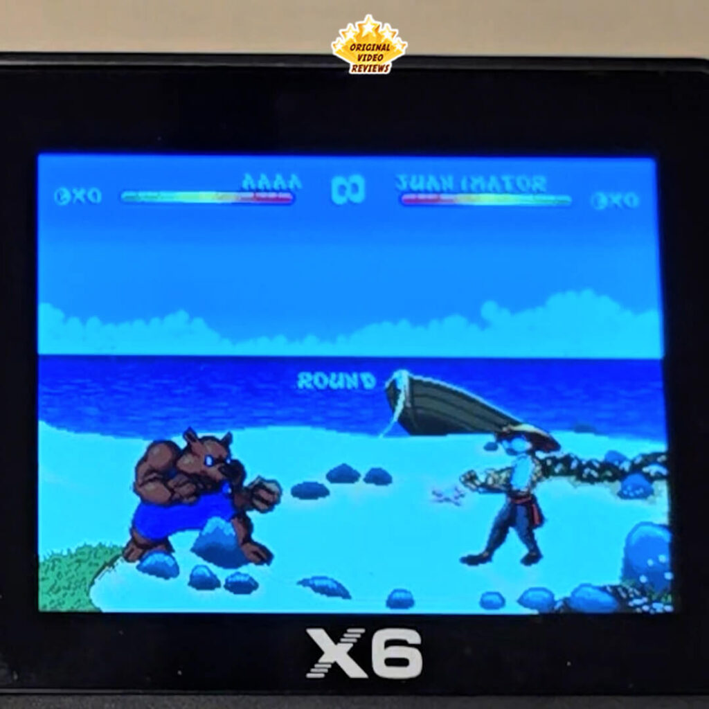 Close-up of the X6 handheld console running the game Brutal: Paws of Fury, showing a fight scene on a beach.
