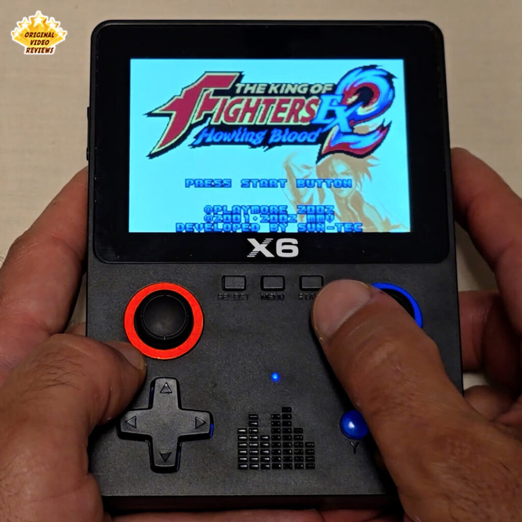 Close-up of the X6 handheld gaming console screen showing the title screen of The King of Fighters EX2: Howling Blood.