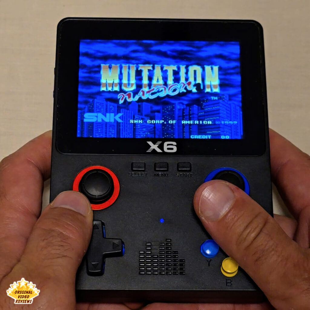 X6 handheld retro gaming console displaying the title screen of "Mutation Nation" by SNK.