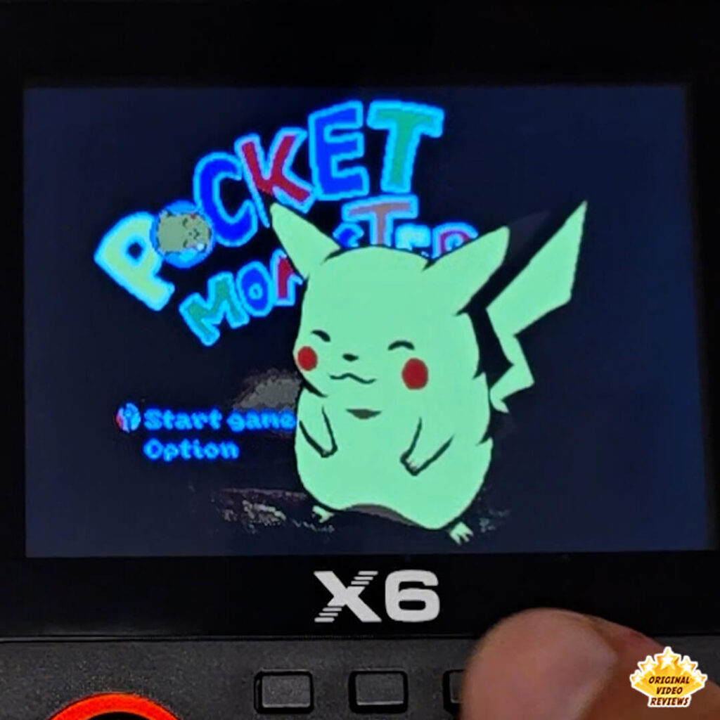 Close-up of the X6 handheld retro gaming console displaying the title screen of Pocket Monsters featuring Pikachu.