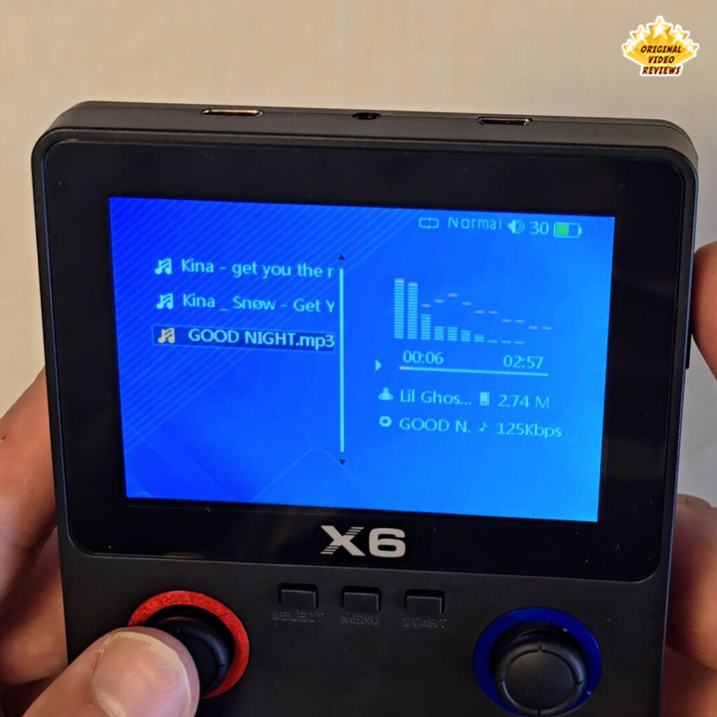 Close-up of the X6 handheld retro gaming console displaying the MP3 player interface.