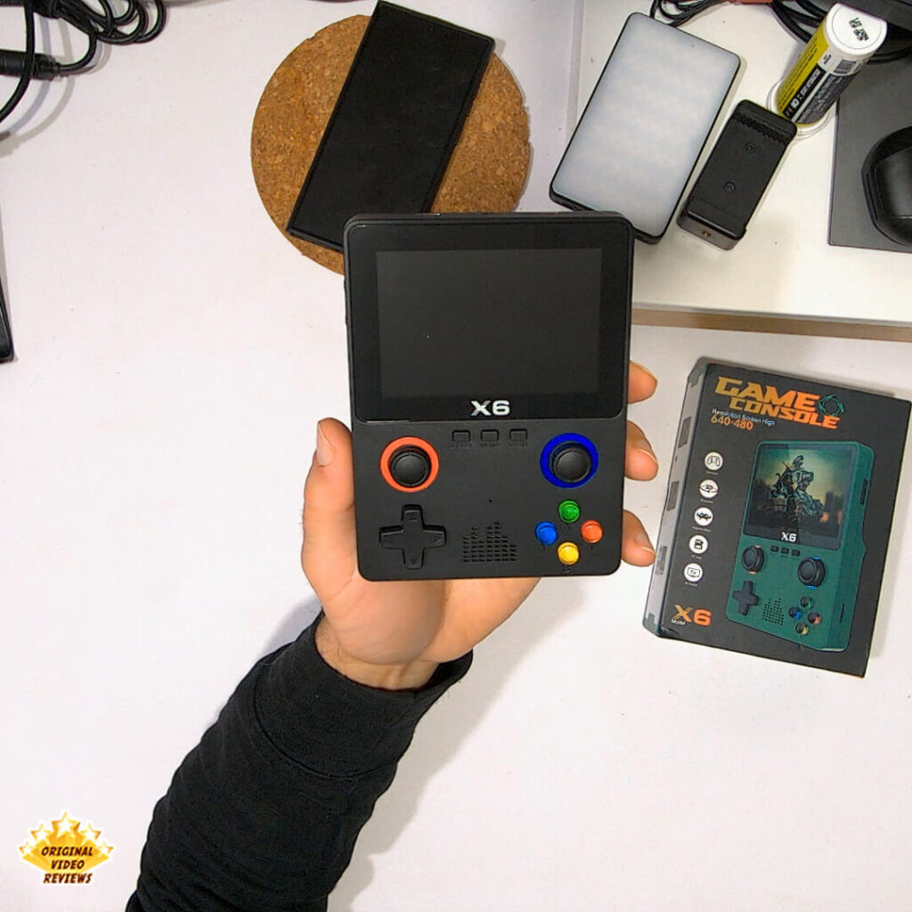 Handheld shot of the X6 retro gaming console alongside its original packaging, featured in the OVR review.