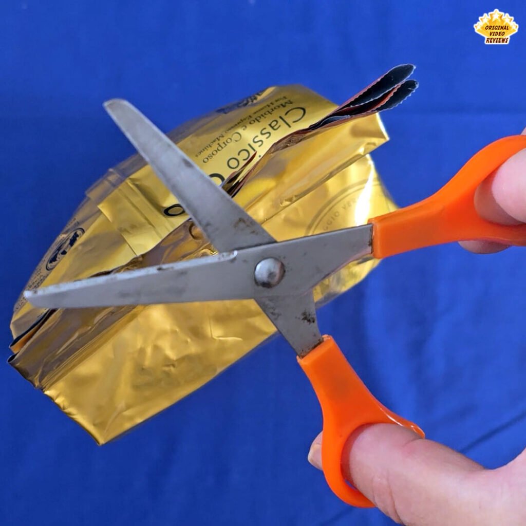 The OVR Guy holding a pair of scissors about to open the Bristot Classico Oro coffee beans package during the unboxing process.