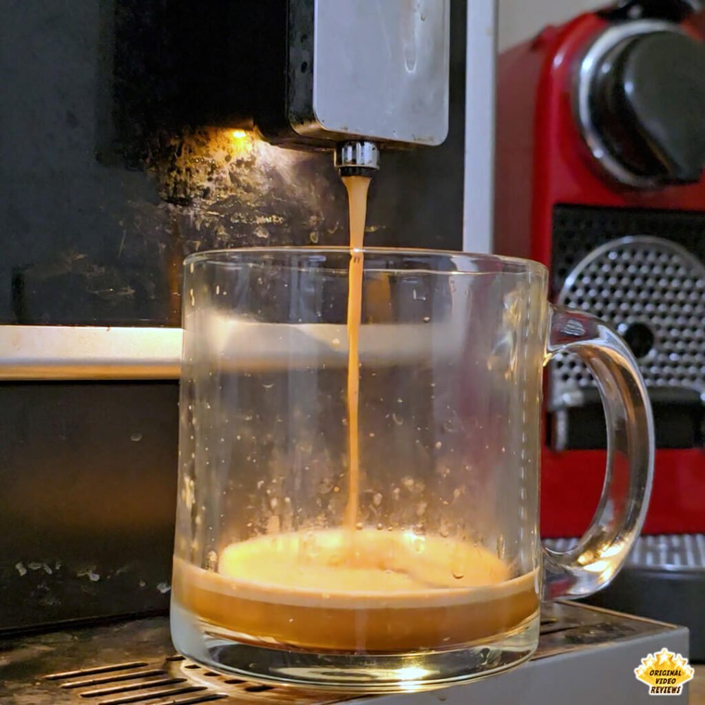 Espresso being poured into a clear glass mug using a home espresso machine. The Bristot Classico Oro coffee shows a smooth crema layer forming on top, highlighting its balanced texture and aroma.