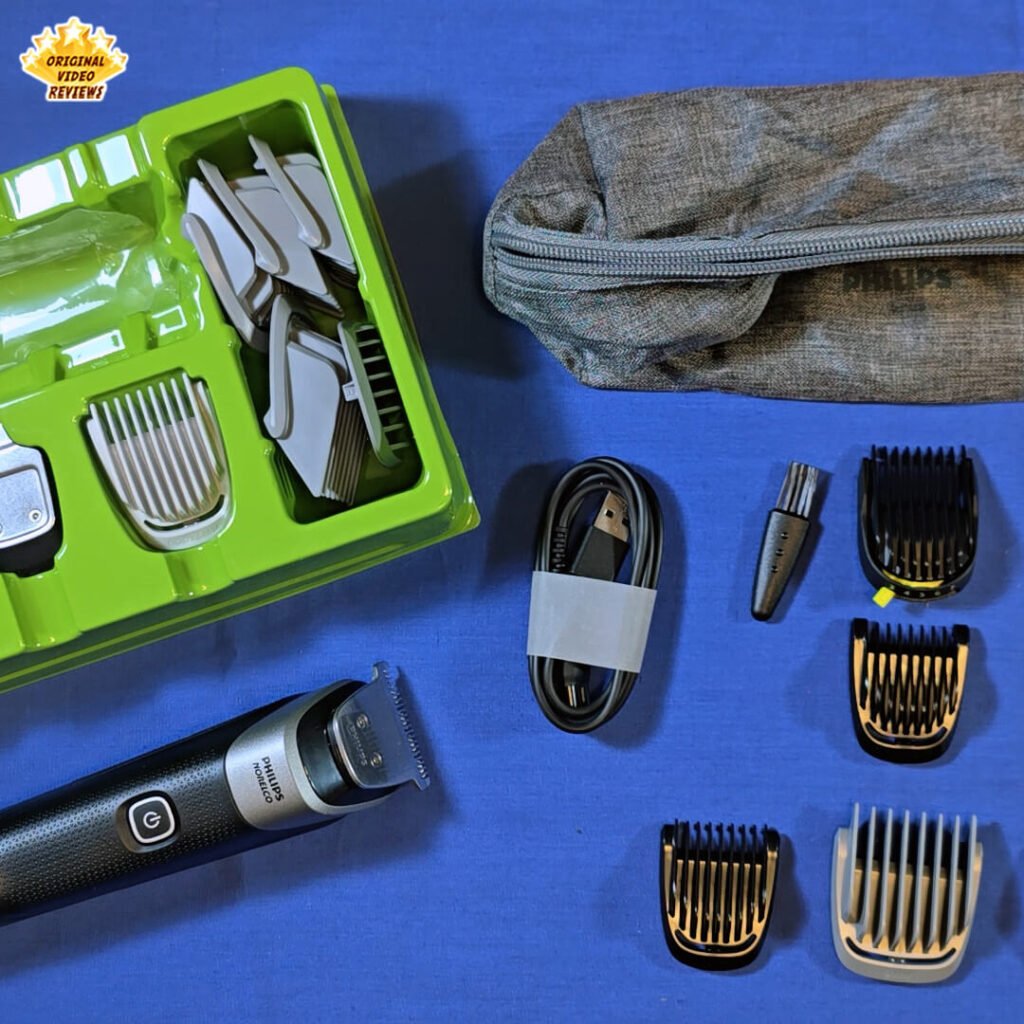 The Philips Norelco Multigroom 5000 MG5970/49 full kit displayed on a blue surface, including trimmer, combs, nose trimmer, USB cable, and travel pouch.