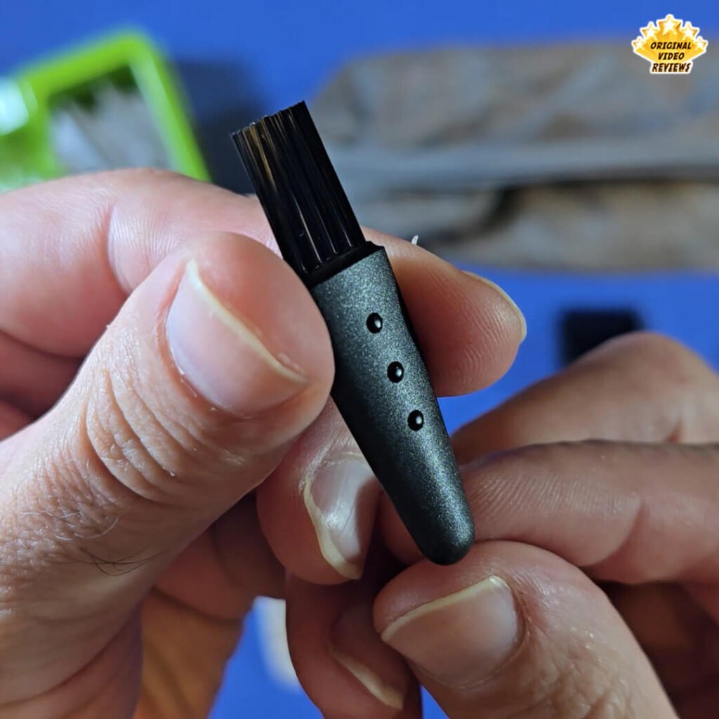 Close-up of the small black cleaning brush included with the Philips Norelco Multigroom 5000 grooming kit.