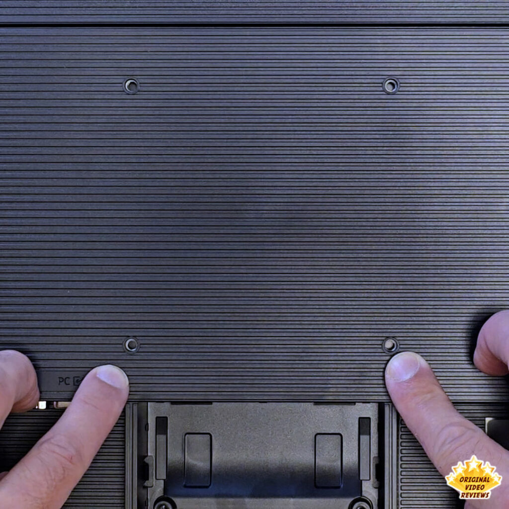 Close-up of the four VESA mount screw holes on the textured rear panel of the Samsung Essential Monitor S3.