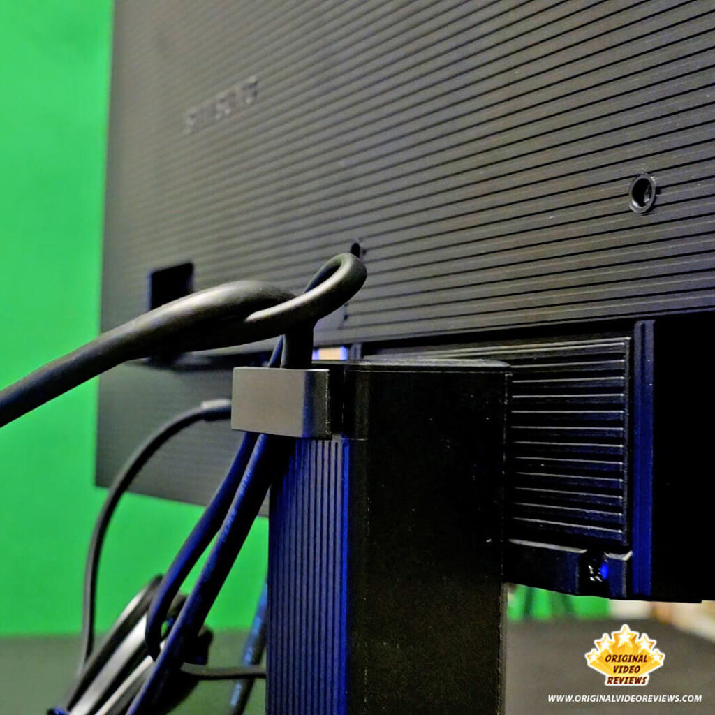 Close-up of the integrated cable management clip on the Samsung Essential Monitor S3 stand holding power and HDMI cables.