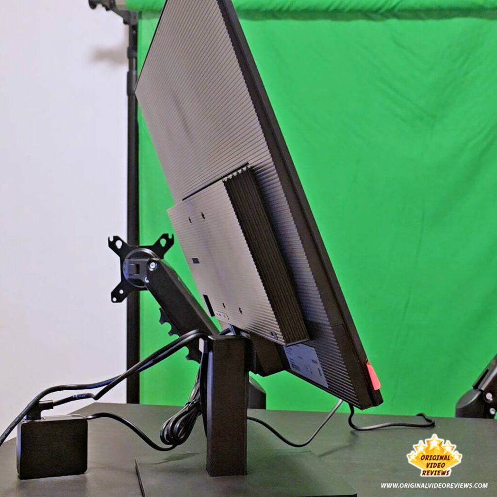 Side view of the Samsung Essential Monitor S3 tilted backward on its stand with the external power adapter visible on the desk.