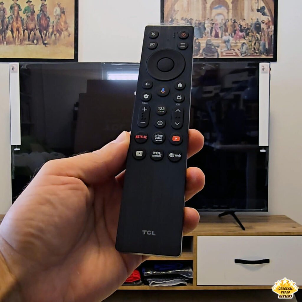 The OVR Guy holding the TCL remote control in front of the TCL P89K 65-inch 4K QLED TV, part of a comprehensive review by Original Video Reviews.