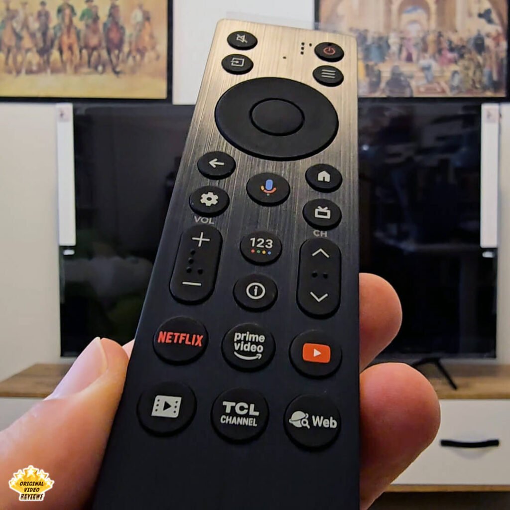 Close-up angled shot of The OVR Guy holding the TCL P89K 65-inch 4K QLED TV remote, highlighting its texture and dedicated streaming buttons, from a review by Original Video Reviews.