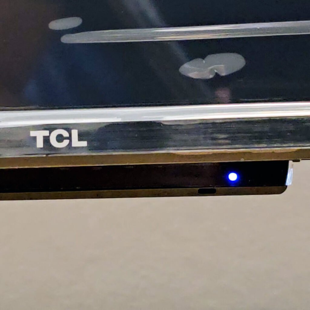 Close-up of the white LED indicator light and remote control receiver on the bottom front bezel of the TCL P89K 65-inch 4K QLED TV, part of a review by Original Video Reviews.