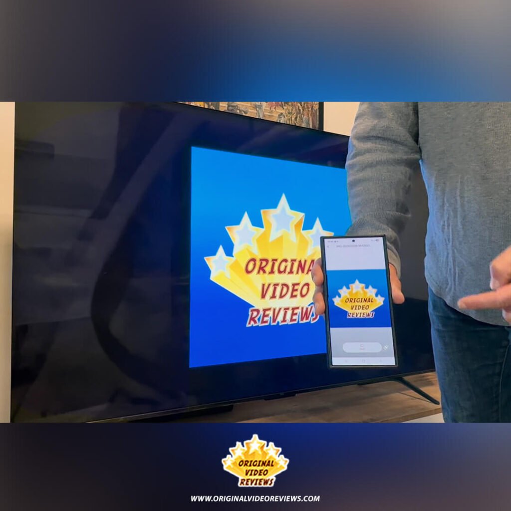 The OVR Guy holding a smartphone displaying the Original Video Reviews logo, which is cast onto the TCL P89K 65-inch 4K QLED TV screen, from a technical review by Original Video Reviews.