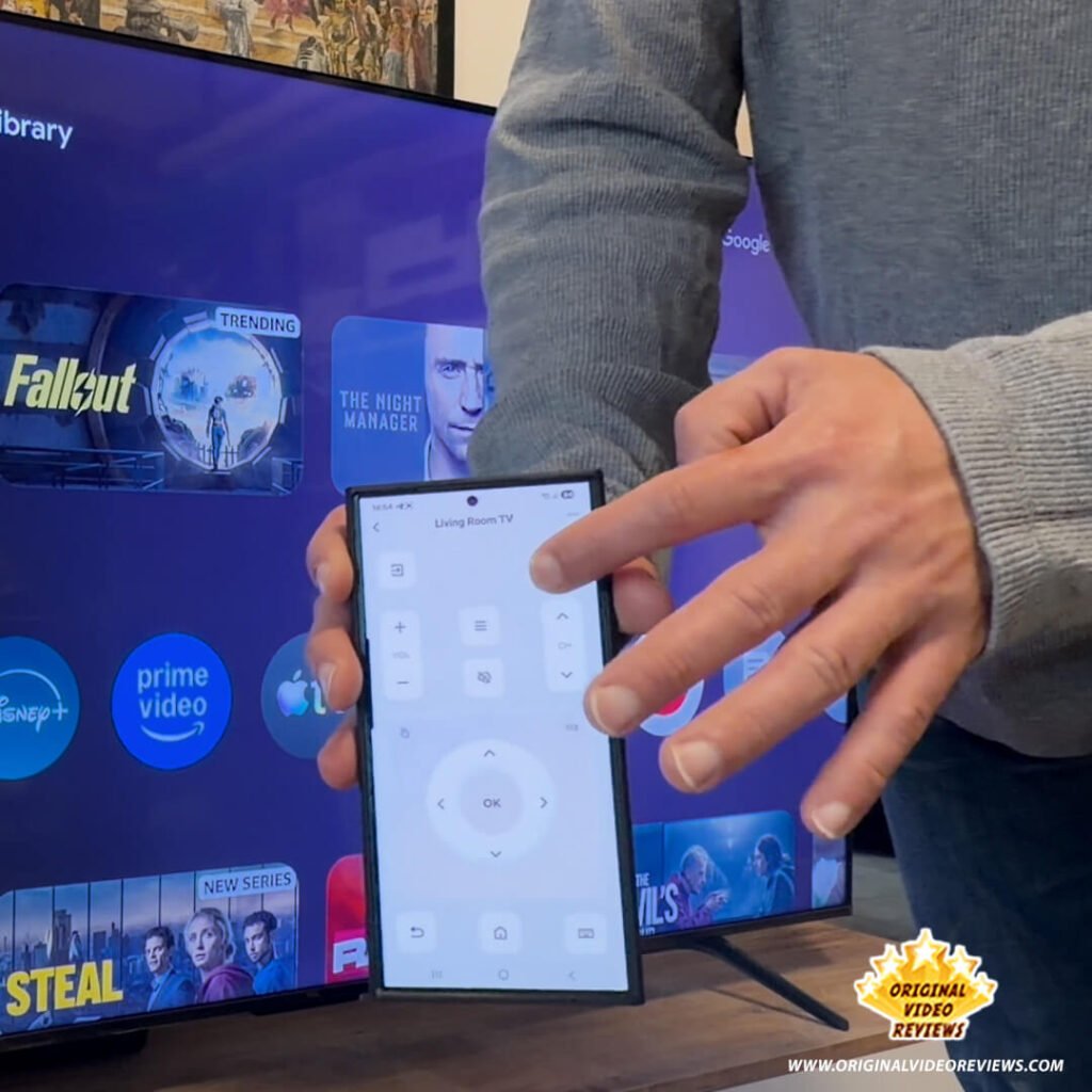 A smartphone displaying a virtual remote control interface within the TCL Home app, used to navigate the TCL P89K 65-inch QLED TV screen visible in the background, from a review by Original Video Reviews.