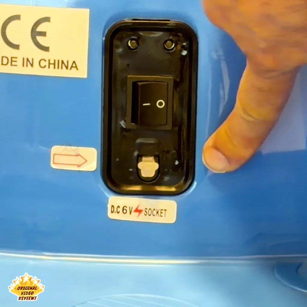 Close-up of the power switch and D.C. 6V charging socket on the Electric Bumper Car for Kids with a finger pointing at the switch