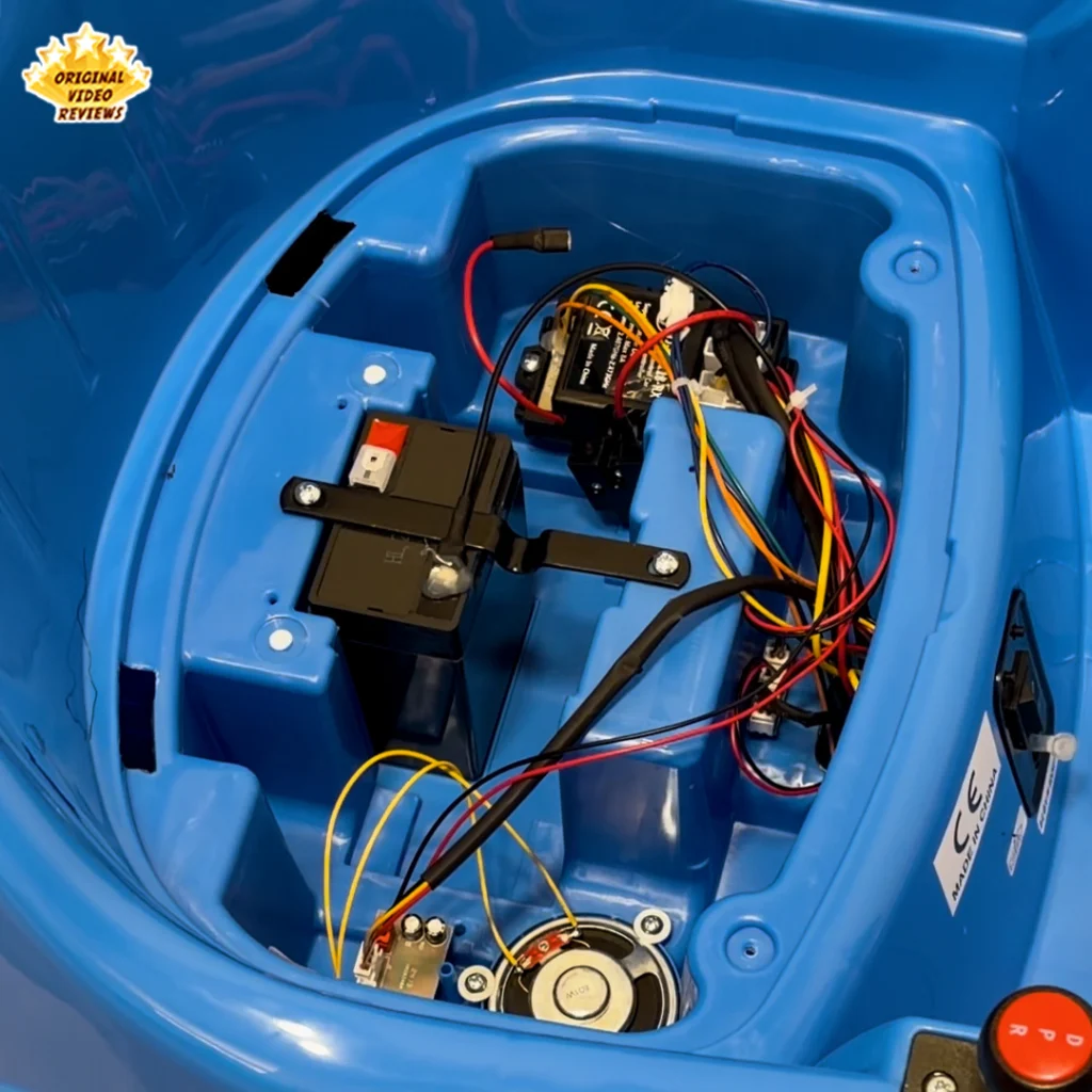 Close-up inside the Electric Bumper Car for Kids showing the sealed battery, receiver module, wiring, and built-in speaker