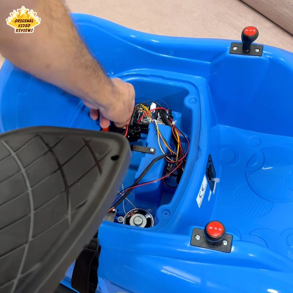 Hand handling the black seat cushion of the Electric Bumper Car for Kids with the internal wiring and both joystick knobs visible