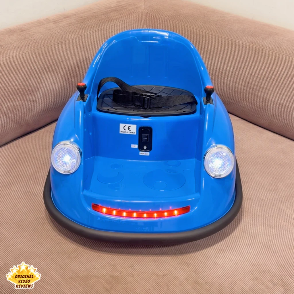 Front view of the blue Electric Bumper Car for Kids sitting on a couch with the red LED light strip lit and the safety harness visible