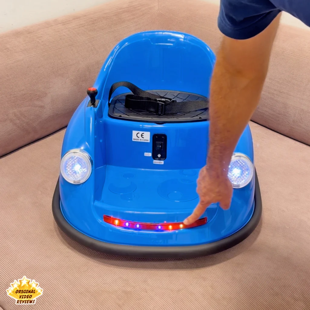 A finger touching the front LED light strip on the Electric Bumper Car for Kids with both headlights and the multicolor LED strip lit