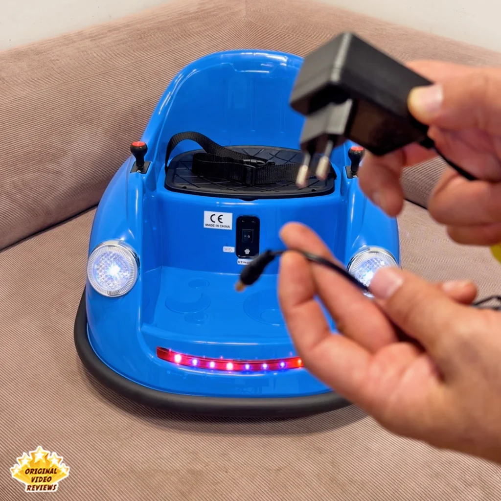Hands holding the black charging transformer and cable for the Electric Bumper Car for Kids near the car’s charging port