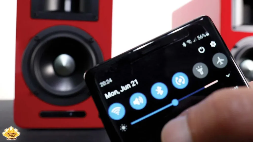 Phone quick settings screen with Bluetooth turned on in front of an AIRPULSE A100 speaker