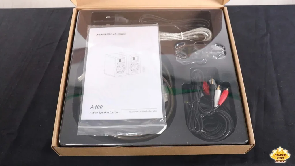 Opened AIRPULSE A100 box with the user manual and cables on top of the foam tray