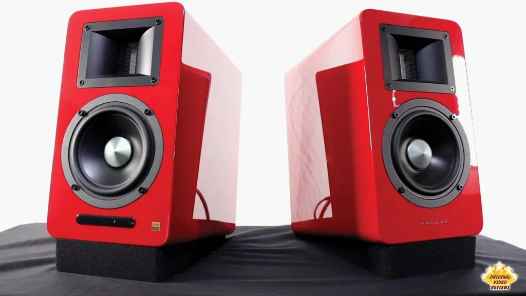 Pair of red AIRPULSE A100 speakers seen from the front, angled slightly inward