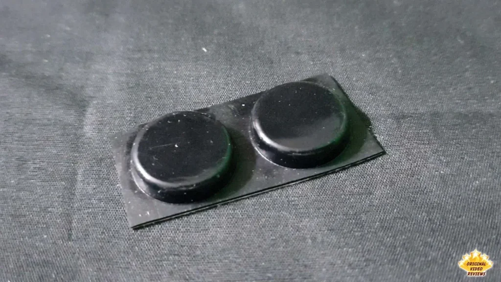 Two black round self-adhesive rubber pads for the AIRPULSE A100 on their backing sheet