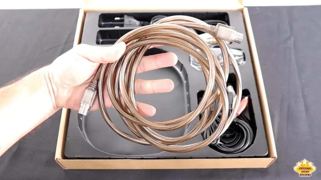 Hand holding the coiled speaker connecting cable that comes with the AIRPULSE A100