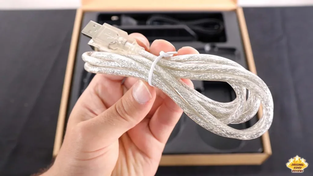 Hand holding the coiled transparent USB cable that comes with the AIRPULSE A100