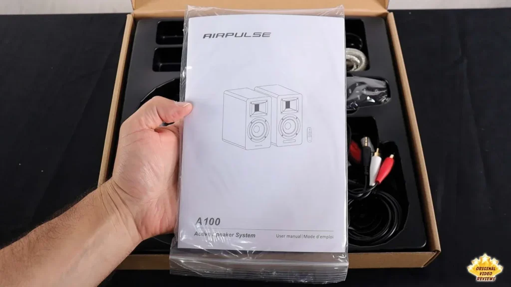 Hand holding the AIRPULSE A100 user manual in its plastic wrap
