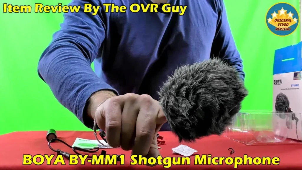 The BOYA BY-MM1 furry windshield held in hand next to the rear of the microphone