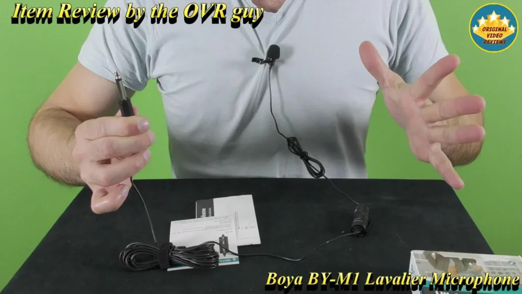 BOYA BY-M1 Lavalier Microphone clipped to a shirt, with the cable and papers on the table