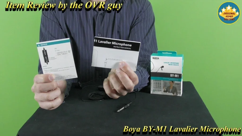 Holding the BOYA BY-M1 Lavalier Microphone user manual pages next to the retail box