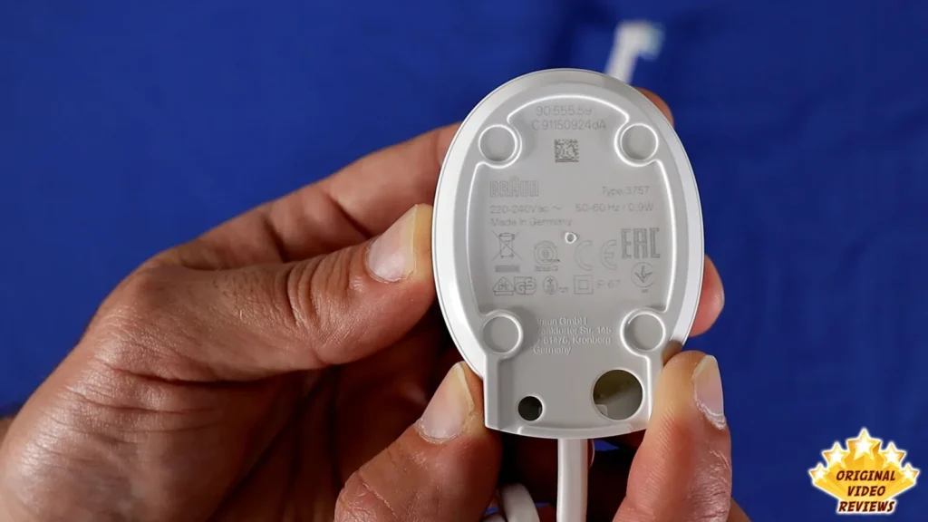 Underside of the Oral-B Vitality charging unit with its label, held in a hand