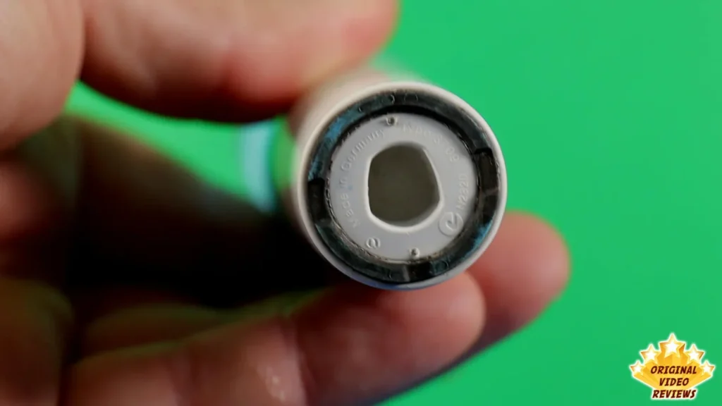 Close-up of the bottom end of the Oral-B Vitality handle held in a hand, green background